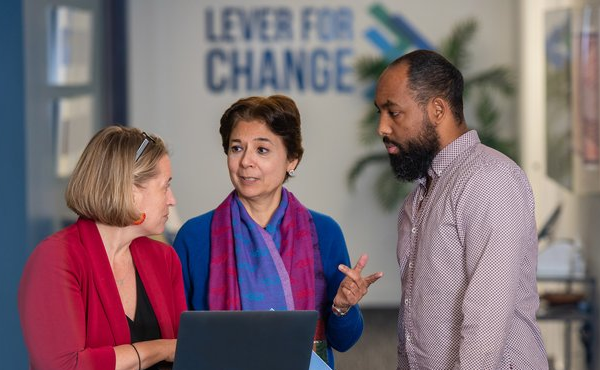 Lever for Change colleagues discuss work in an office hallway